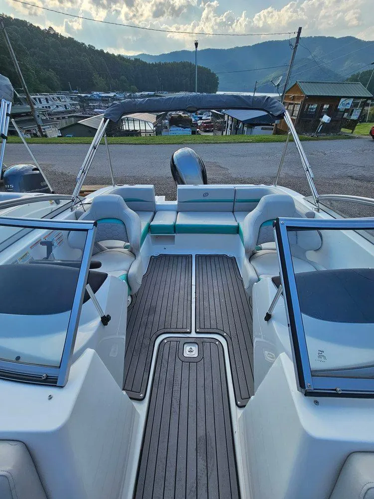 Slide: The Image of 2024 Hurricane SD 191 OB boat interior with seating and windshield, docked near mountains. - 10