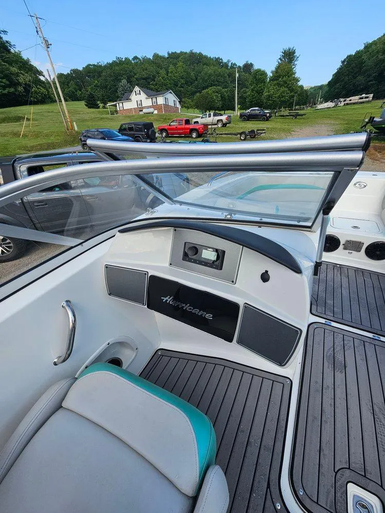 Slide: The Image of 2024 Hurricane SD 191 OB boat interior with seating and dashboard, parked outdoors. - 8
