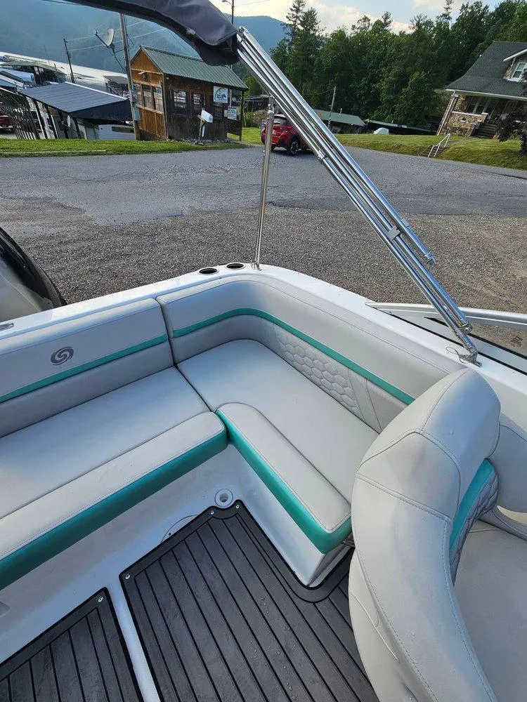 Slide: The Image of 2024 Hurricane SD 191 OB boat interior with white and teal seating, docked near rustic buildings. - 9