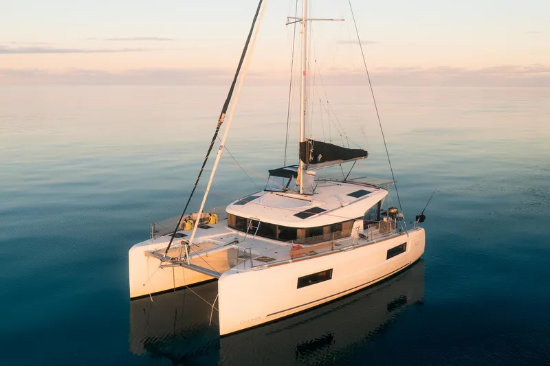 Slide: The Image of 2023 Lagoon 40 catamaran sailing on calm waters at sunset. - 2