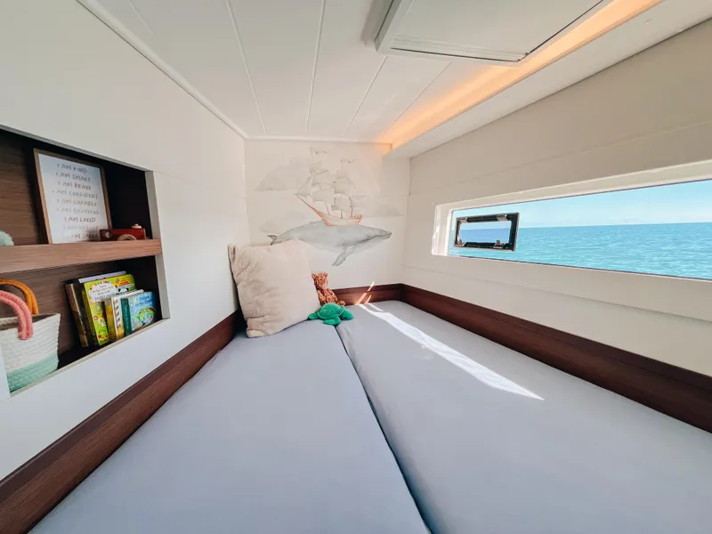 Slide: The Image of Cozy cabin interior of 2023 Lagoon 40 catamaran with ocean view and bookshelf. - 34
