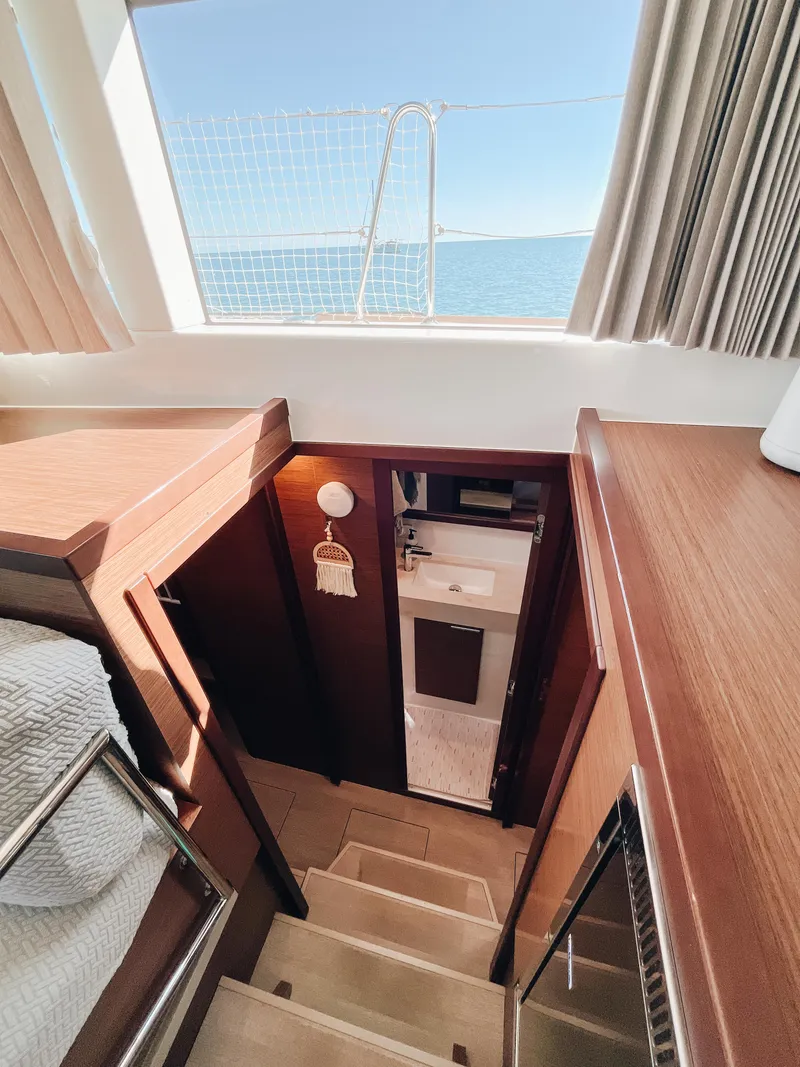 Slide: The Image of Interior of 2023 Lagoon 40 yacht, featuring wooden stairs and a bathroom view. - 43