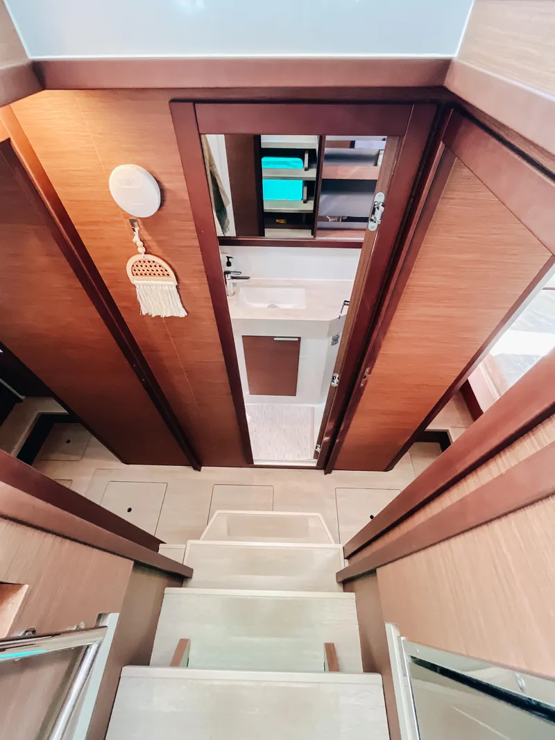 Slide: The Image of 2023 Lagoon 40 interior with wooden stairs leading to a modern bathroom. - 44