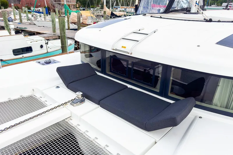 Slide: The Image of 2023 Lagoon 40 catamaran with cushioned deck seating at marina. - 49