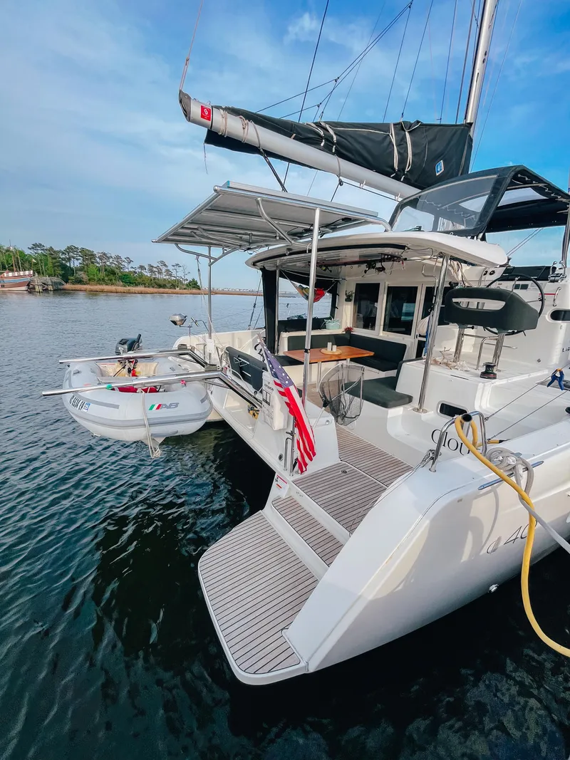 Slide: The Image of 2023 Lagoon 40 catamaran docked, featuring a spacious deck and attached dinghy. - 7