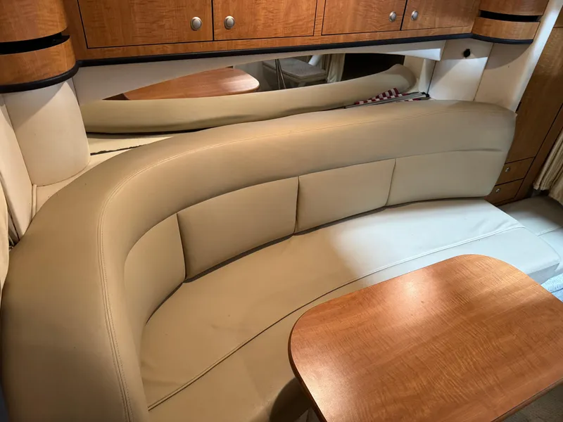 Slide: The Image of Interior of 2005 Sea Ray 300 Sundancer with curved seating and wooden table. - 14