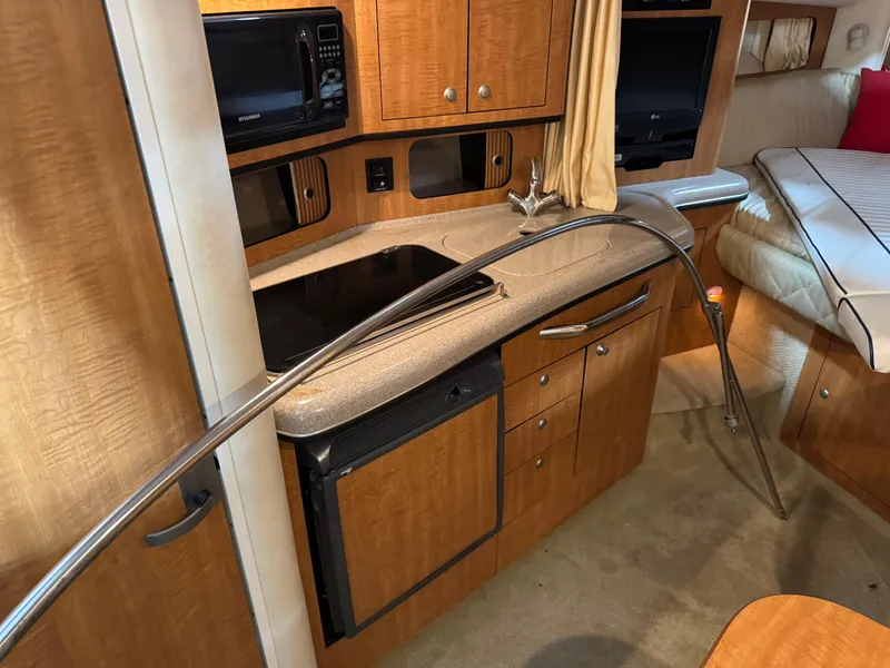 Slide: The Image of Interior of 2005 Sea Ray 300 Sundancer with kitchenette and cozy seating area. - 17