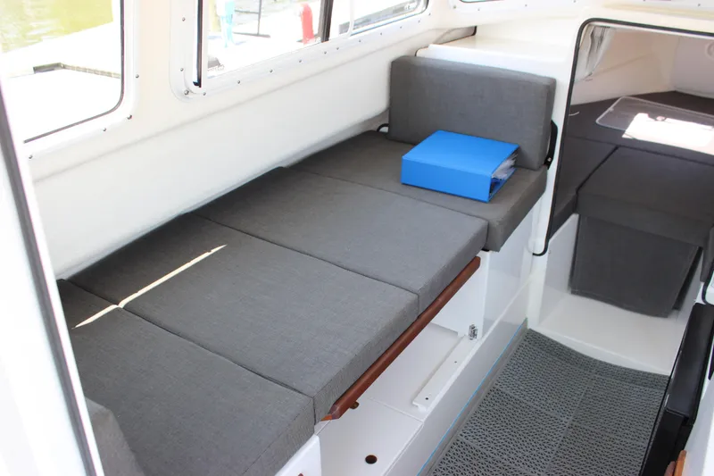 Slide: The Image of 2023 C-Dory 22' Cruiser interior with gray seating and blue folder on bench. - 13
