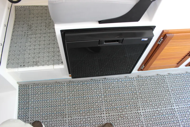 Slide: The Image of Interior of 2023 C-Dory 22' Cruiser with fridge and wooden cabinets. - 19