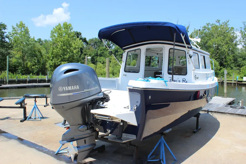 Slide: The Image of 2023 C-Dory 22' Cruiser with Yamaha outboard motor, docked near lush greenery. - 22