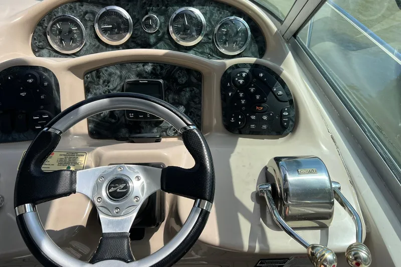 Slide: The Image of Dashboard of a 2003 Sea Ray 320 Sundancer boat with steering wheel and throttle controls. - 13