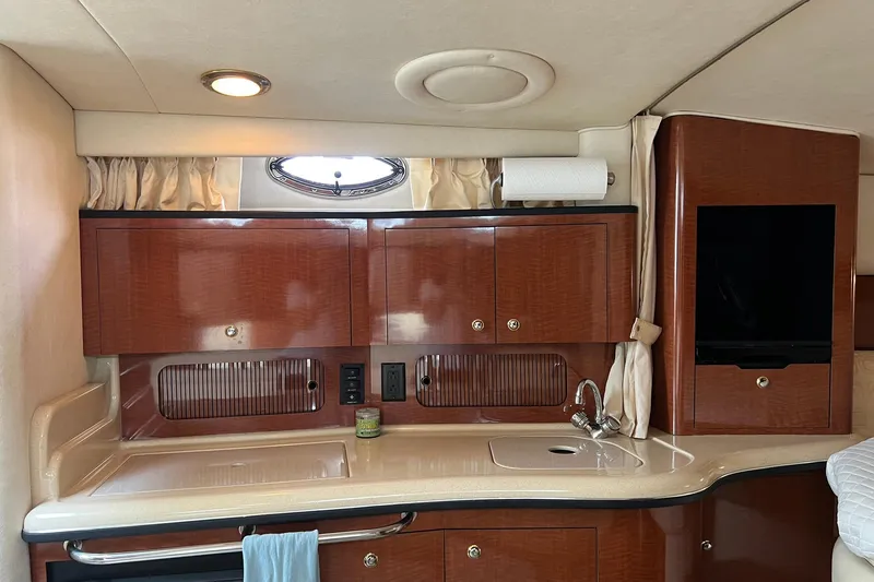 Slide: The Image of 2003 Sea Ray 320 Sundancer interior with wooden cabinets and compact kitchenette. - 19