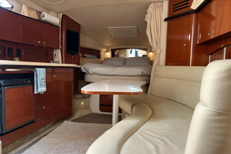 Slide: The Image of 2003 Sea Ray 320 Sundancer interior with cozy seating, kitchenette, and bed. - 24
