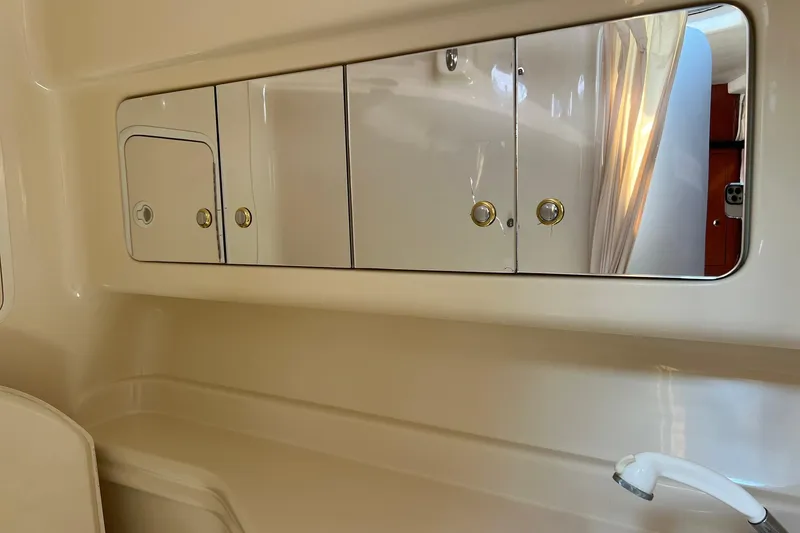 Slide: The Image of 2003 Sea Ray 320 Sundancer bathroom with mirrored cabinets and a white faucet. - 32