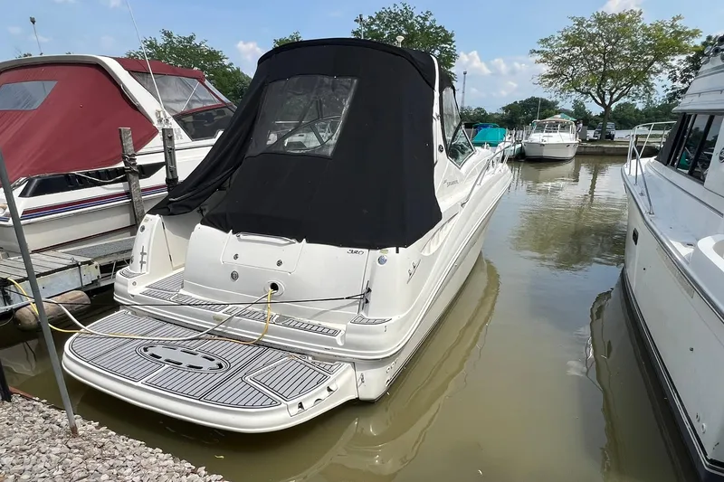 Slide: The Image of 2003 Sea Ray 320 Sundancer docked at marina, rear view with black cover. - 35