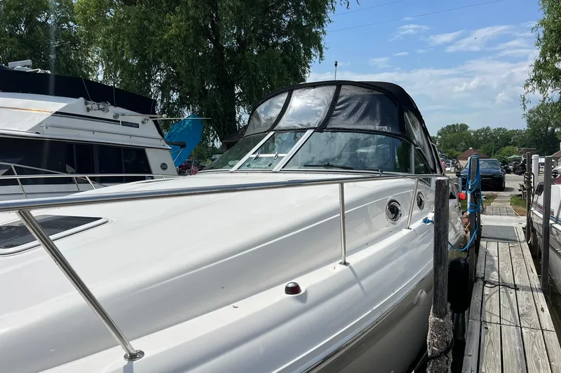 Slide: The Image of 2003 Sea Ray 320 Sundancer docked, featuring sleek design and canopy under a clear sky. - 36