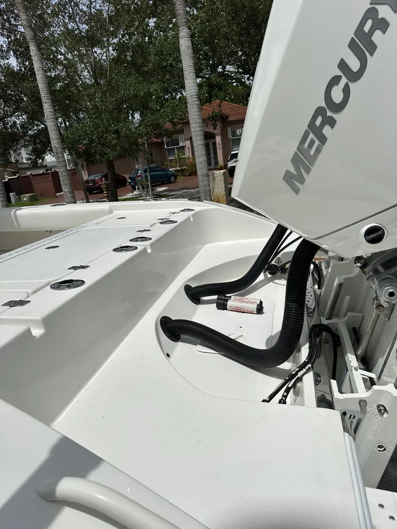 Slide: The Image of White Mercury outboard engine on a 2019 Young 27 boat, parked near trees. - 10