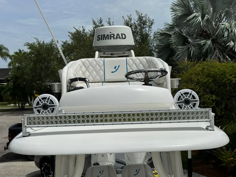 Slide: The Image of White Young 27 boat helm with Simrad electronics and speakers, surrounded by lush greenery. - 11