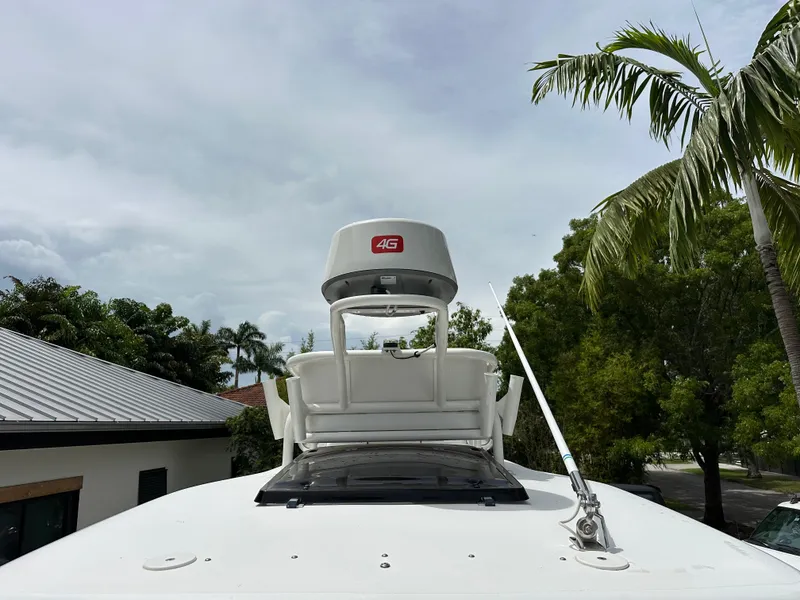 Slide: The Image of Boat roof with 4G radar and antenna, surrounded by palm trees, under cloudy sky. - 13