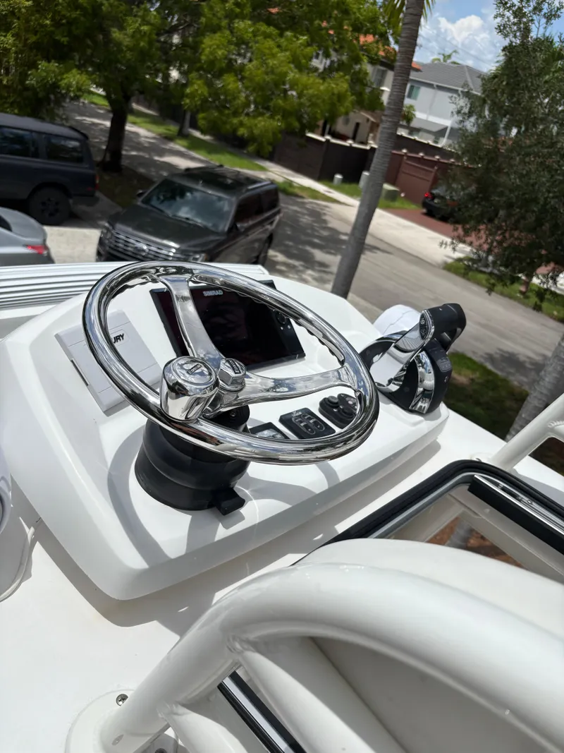Slide: The Image of Steering wheel and controls of a 2019 Young 27 boat, parked in a residential area. - 18