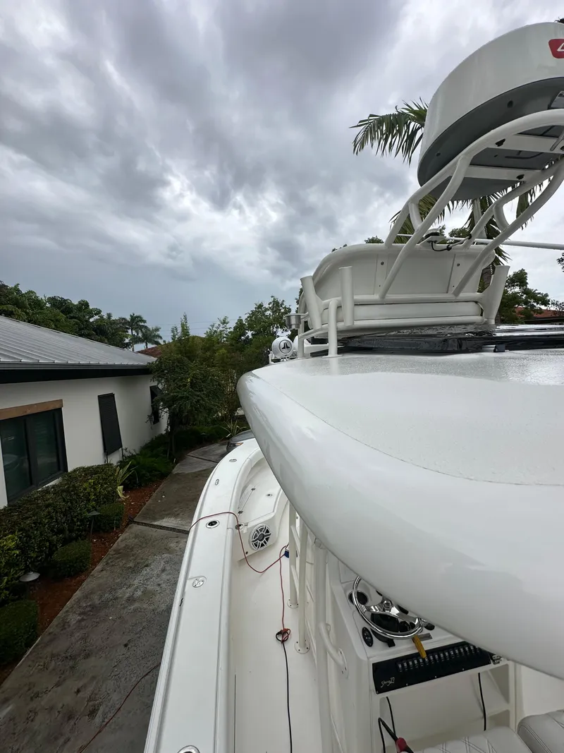 Slide: The Image of White Young 27 boat docked, cloudy sky, lush greenery, residential background, 2019 model. - 19