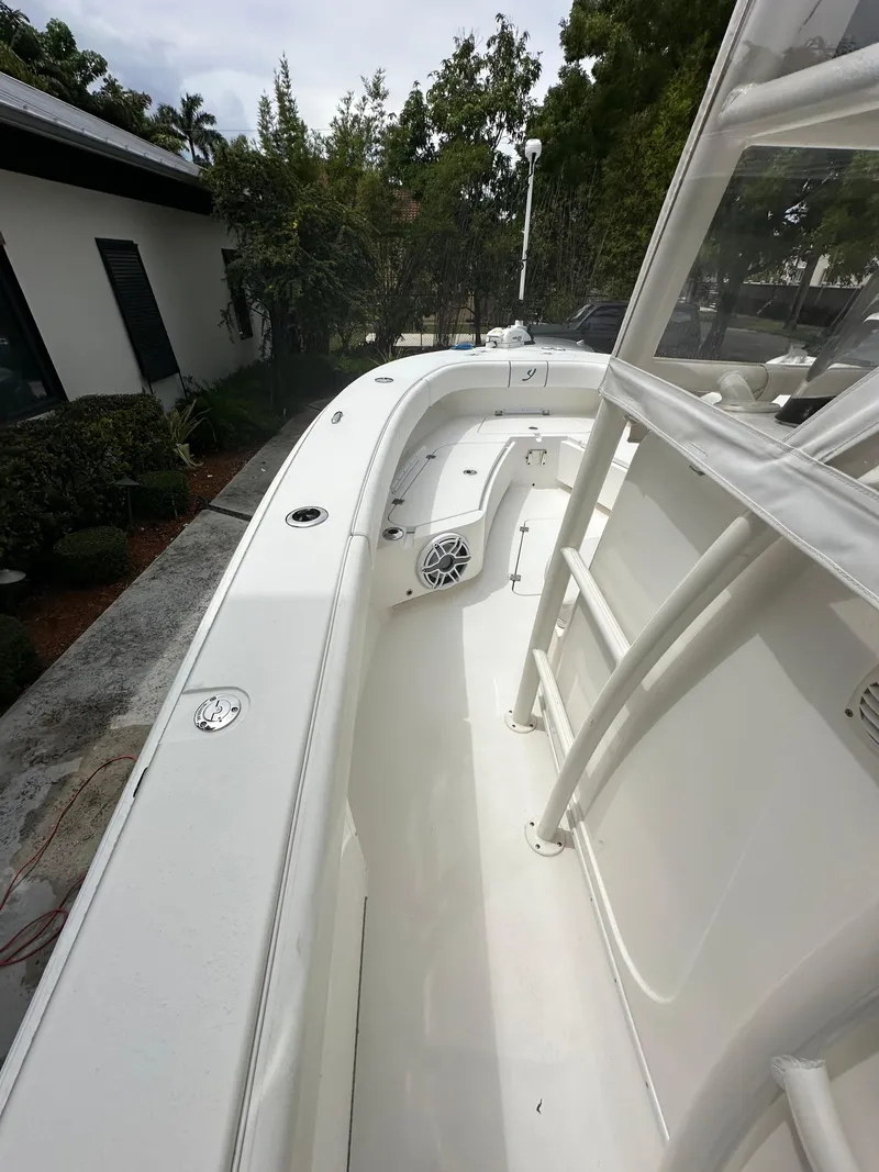 Slide: The Image of White 2019 Young 27 boat deck with seating and speaker, surrounded by greenery. - 20