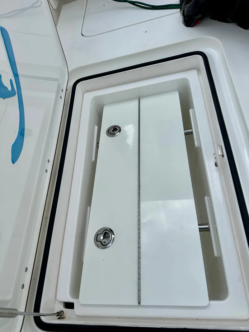Slide: The Image of Open storage compartment on a 2019 Young 27 boat, featuring a white lid and secure latches. - 25