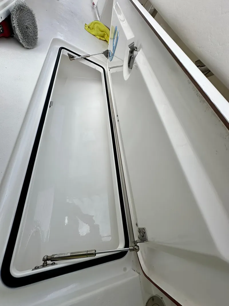 Slide: The Image of Open storage compartment on a 2019 Young 27 boat, with cleaning supplies nearby. - 30