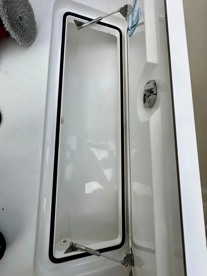 Slide: The Image of Open storage compartment on a 2019 Young 27 boat, featuring stainless steel hinges. - 31