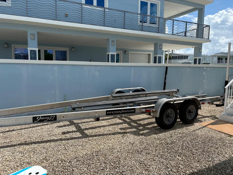 Slide: The Image of Boat trailer "Young 27" parked on gravel near a modern blue house, 2019 model. - 40