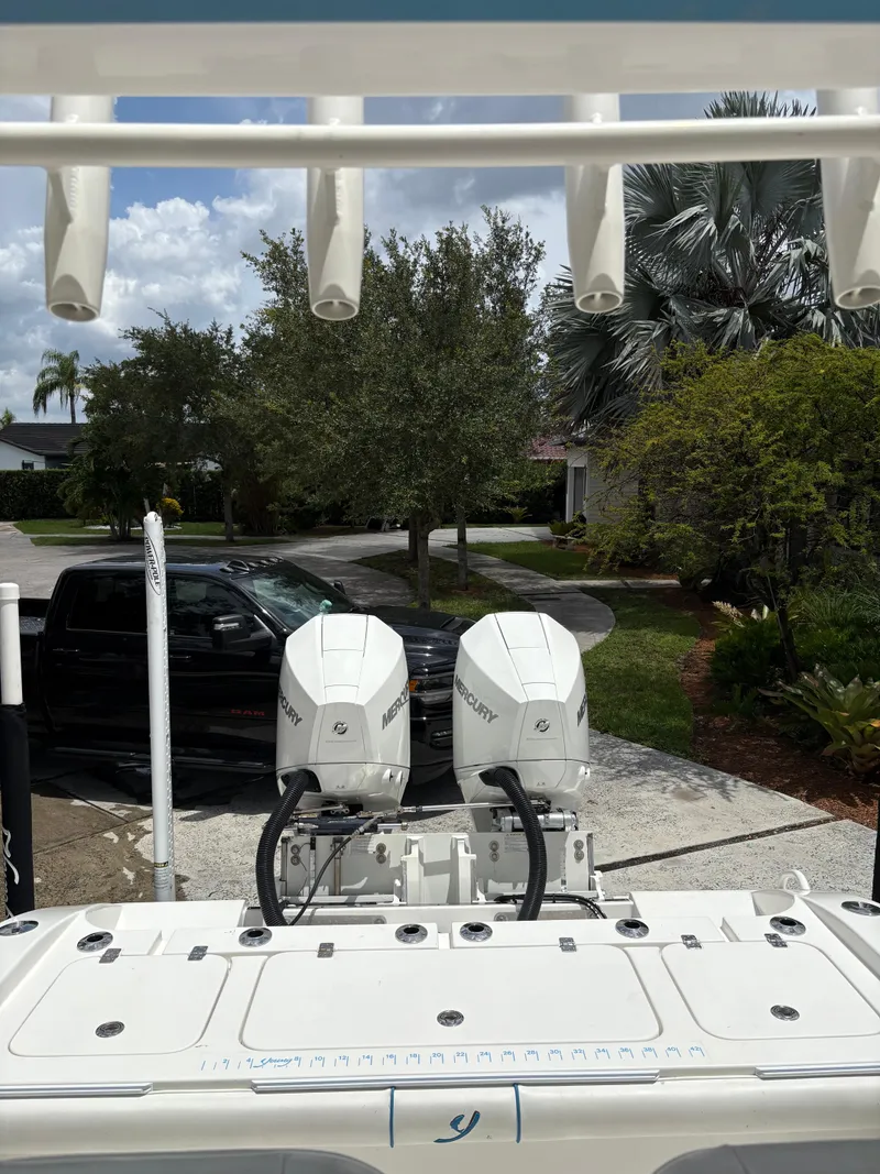 Slide: The Image of Boat with dual Mercury engines parked in driveway, surrounded by trees and a black truck. - 9