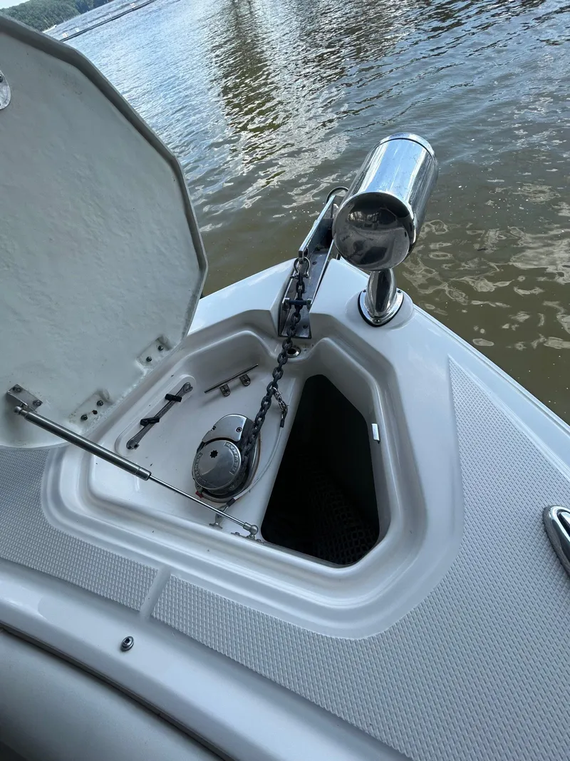 Slide: The Image of Open anchor compartment on 2014 Chaparral 327 SSX boat by the water. - 13