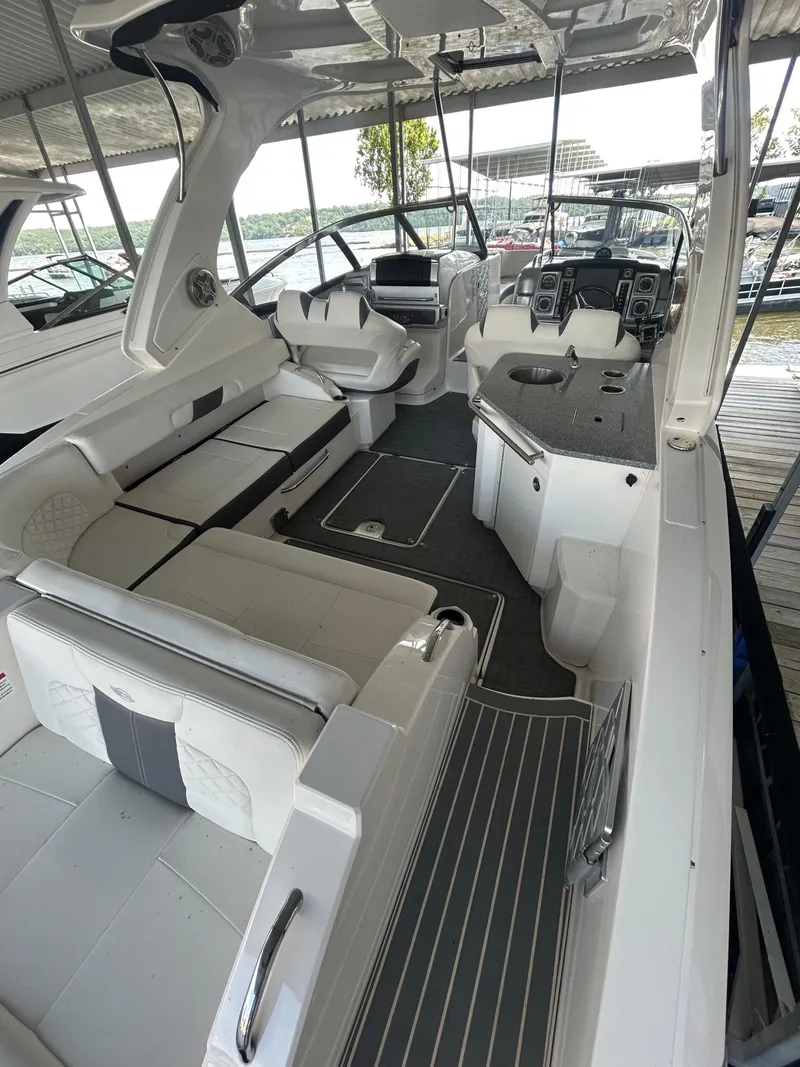 Slide: The Image of 2014 Chaparral 327 SSX boat interior with seating and helm, docked under a canopy. - 5