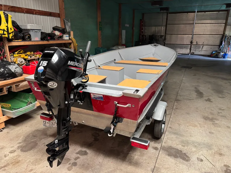 Slide: The Image of 2023 Lund SSV-14 Tiller boat with Mercury 15 engine in a garage setting. - 2