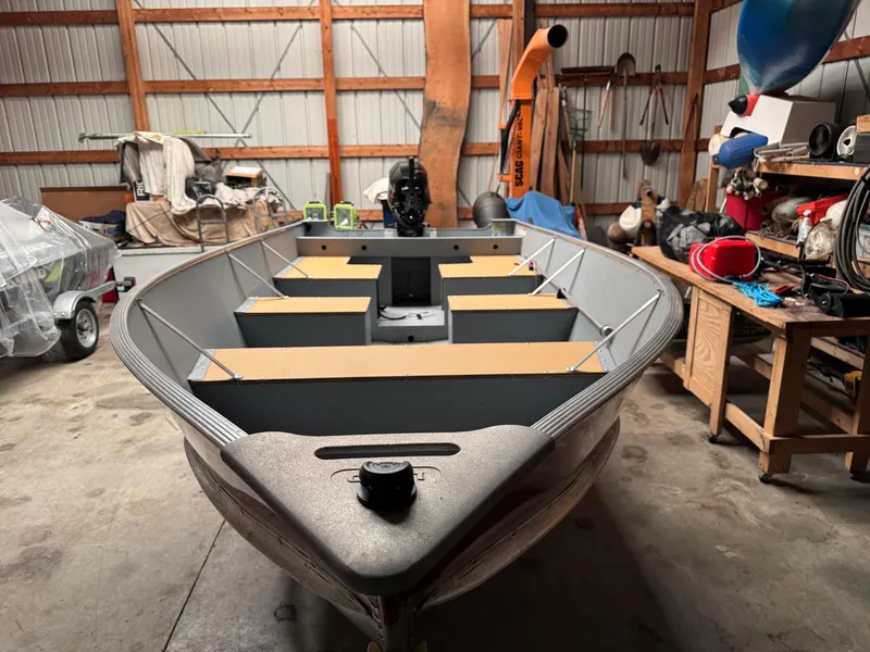 Slide: The Image of 2023 Lund SSV-14 Tiller boat in a garage, surrounded by tools and equipment. - 3