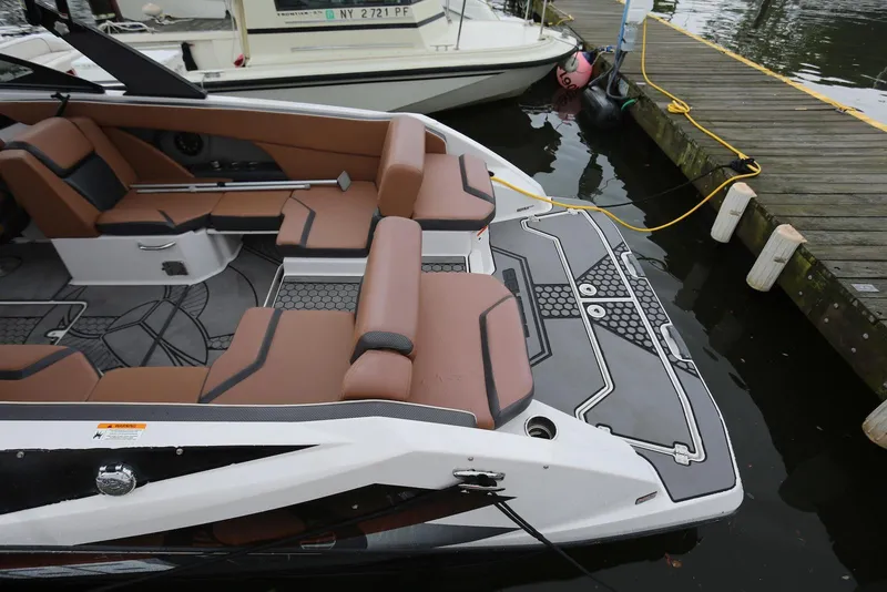 Slide: The Image of 2017 Scarab 255 Impulse boat docked, featuring brown seating and modern design elements. - 13