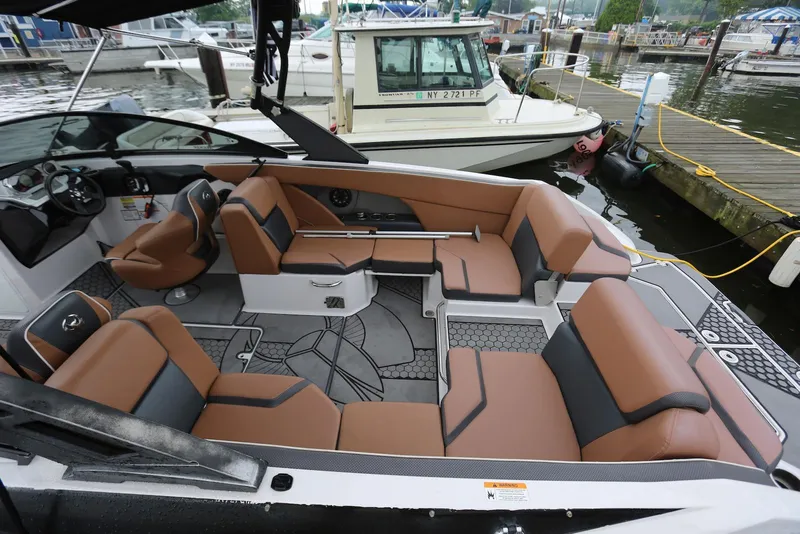 Slide: The Image of 2017 Scarab 255 Impulse boat interior with brown and black seating, docked at a marina. - 14