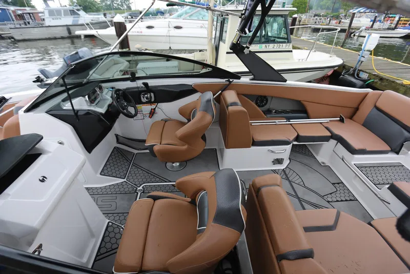 Slide: The Image of 2017 Scarab 255 Impulse boat interior with brown seating and modern dashboard at a marina. - 15