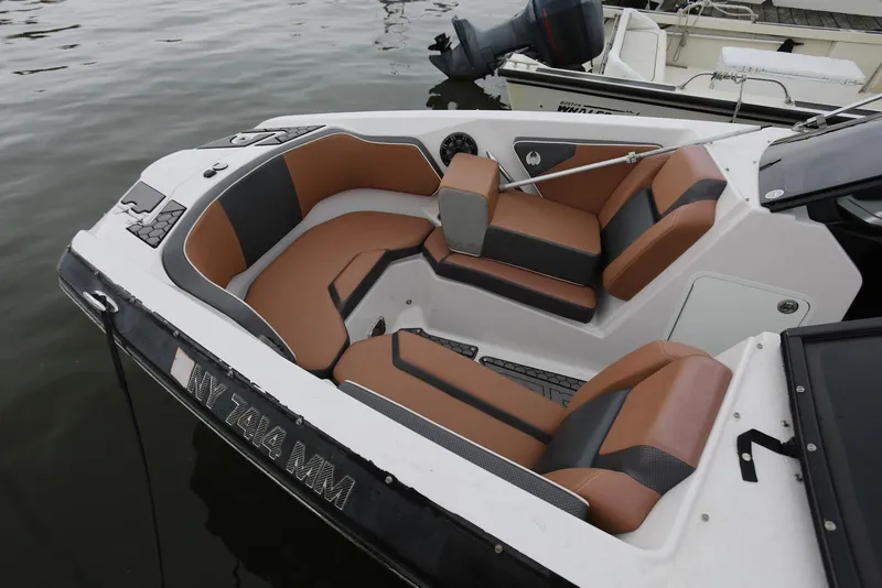 Slide: The Image of 2017 Scarab 255 Impulse boat with brown and black seating, docked on calm water. - 17
