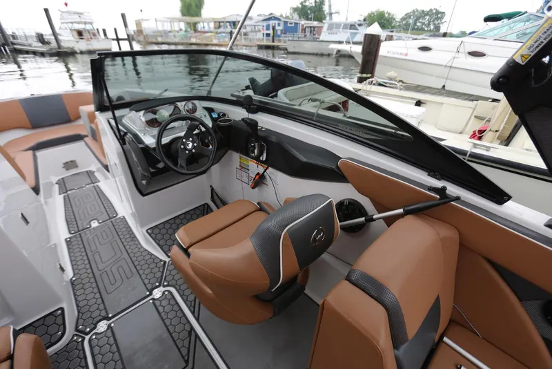 Slide: The Image of 2017 Scarab 255 Impulse boat interior with tan seating and modern dashboard at a marina. - 29