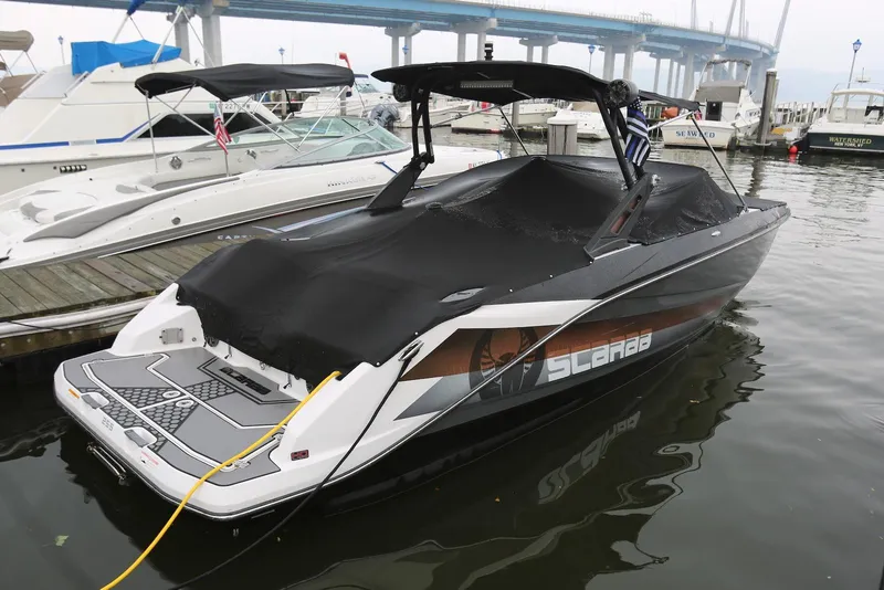 Slide: The Image of 2017 Scarab 255 Impulse boat docked, covered, with bridge in background. - 5