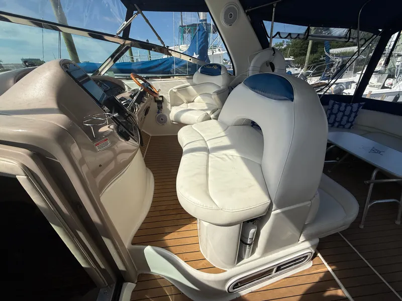 Slide: The Image of 2003 Sea Ray 380 Sundancer cockpit with white seating and wooden flooring. - 15