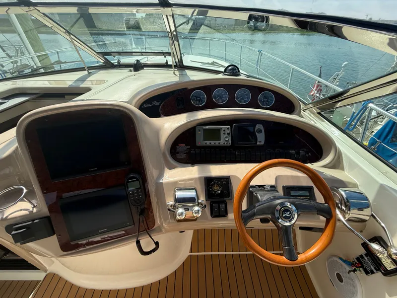 Slide: The Image of 2003 Sea Ray 380 Sundancer helm with wood steering wheel and navigation instruments. - 16