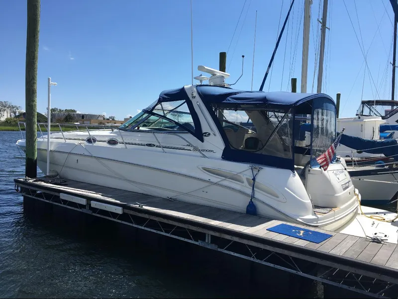 Slide: The Image of 2003 Sea Ray 380 Sundancer yacht docked at marina, featuring blue canopy and sleek design. - 2