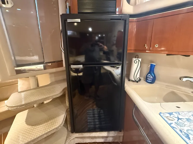 Slide: The Image of Interior of 2003 Sea Ray 380 Sundancer yacht with kitchenette and black refrigerator. - 22