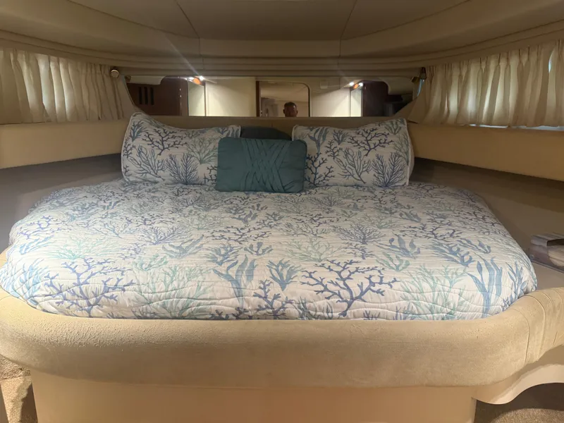 Slide: The Image of 2003 Sea Ray 380 Sundancer cabin with a cozy, ocean-themed bedspread and soft lighting. - 24