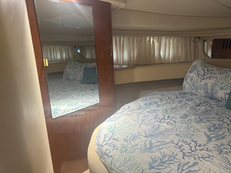 Slide: The Image of 2003 Sea Ray 380 Sundancer cabin with mirror, bed, and patterned bedding. - 25