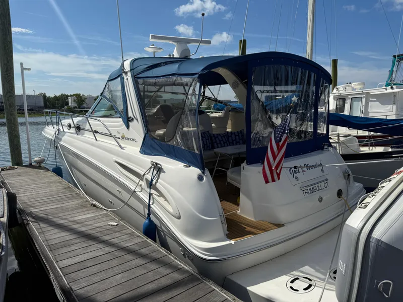 Slide: The Image of 2003 Sea Ray 380 Sundancer docked, featuring blue canopy and American flag. - 9