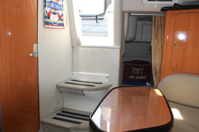 Slide: The Image of Interior of 2000 Regal Commodore 2760 boat with stairs, table, and life jackets. - 20