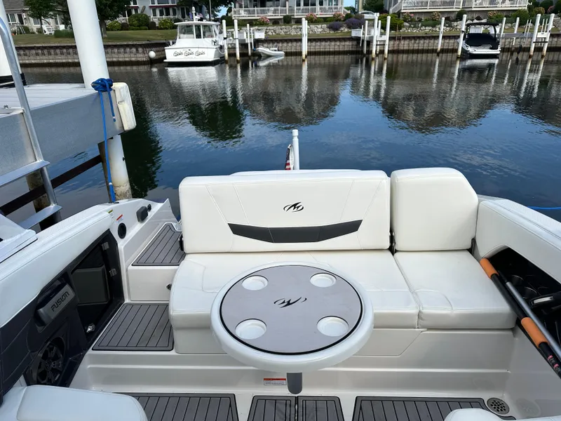 Slide: The Image of 2014 Monterey 268 Super Sport boat interior with seating and table, docked by calm water. - 22